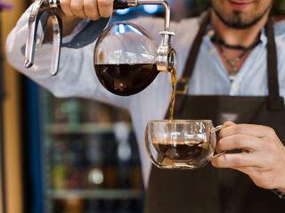 Barista schenkt fertig gebrühten Kaffee aus dem Syphon in eine Tasse ein