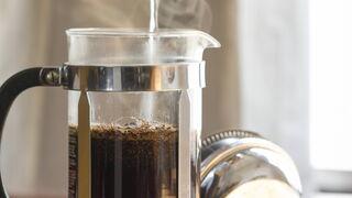 Kaffeepulver in einer Stempelkanne wird mit heißem Wasser aufgefüllt