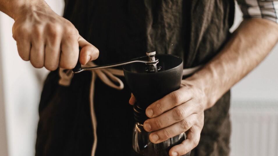 Barista benutzt eine handbetriebene Kaffeemühle
