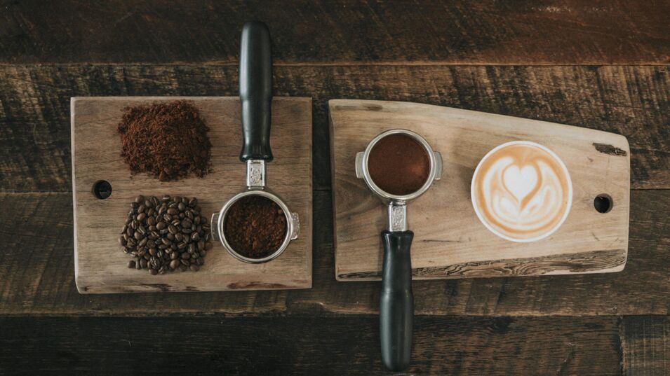 Cappuccino auf Holzbrett mit Kaffeebohnen auf dem Tisch