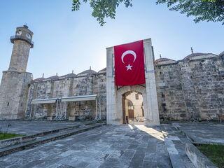 Historisches Gebäude mit einer großen türkischen Flagge über dem Eingang und einem Uhrturm im Hintergrund.