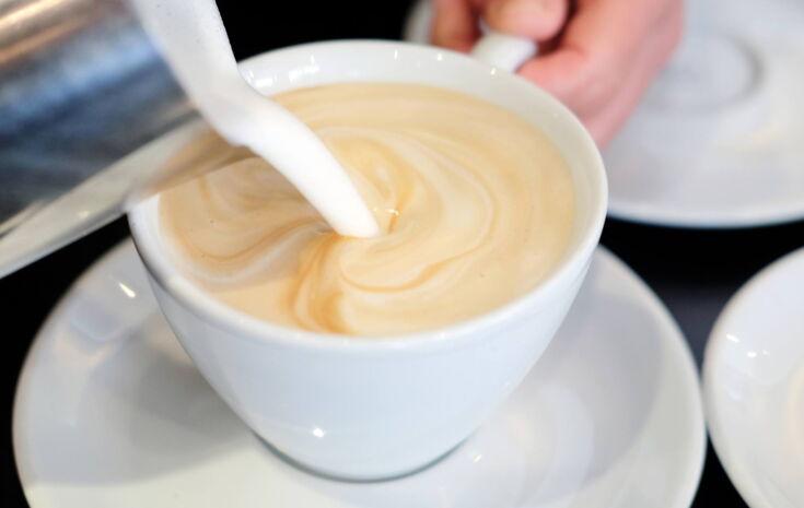 Milch wird in einem Kaffee gekippt