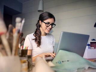 Laechelnde Frau arbeitet am Laptop