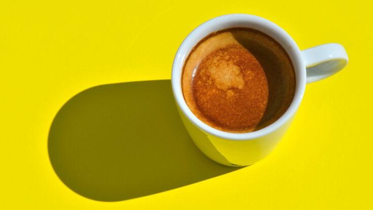 Eine Tasse Kaffee Crema steht auf gelbem Untergrund