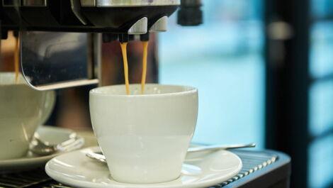 Kaffee aus dem Kaffeeautomaten läuft in Tasse