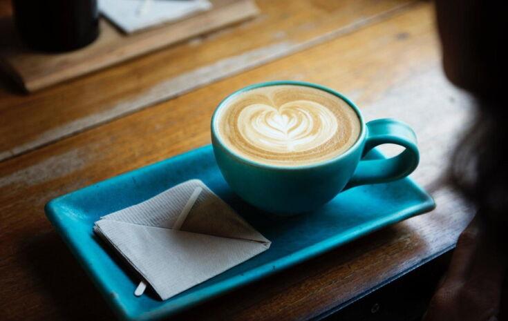 Tasse Kaffee wird mit Serviette auf Unterteller serviert