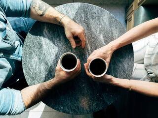 paar sitzt gegenueber und trinkt kaffee von oben