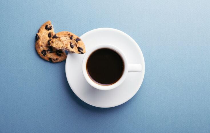 Schwarzer Kaffee serviert mit einem Cookie auf einer Untertasse