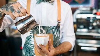 Barista arbeitet an der Bar und bereitet Latte-Art vor