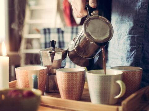 Kaffee wird aus einem Espressokocher in Tassen gegossen