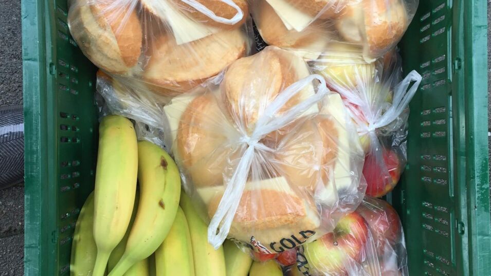 Ein Lunchpaket der Kindertafel mit belegten Brötchen, Bananen und Äpfeln
