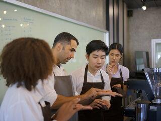 Die Espressomaschine wird für neue junge Mitarbeiter erklärt