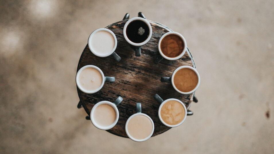 8 Kaffeetassen auf einem Holztisch