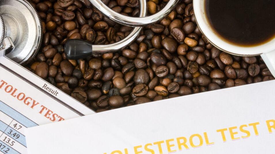 Stethoskop, Cholesterintestergebnis und eine Tasse Kaffee auf Kaffeebohnen.