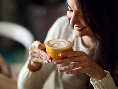 junge Frau trinkt Kaffee aus einer gelben Tasse