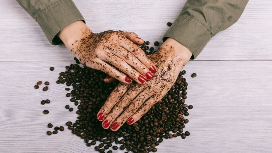 Damenhände reiben sich mit Kaffeepulver ein