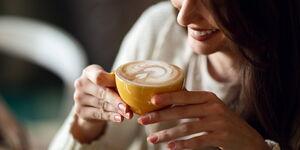 junge Frau trinkt Kaffee aus einer gelben Tasse