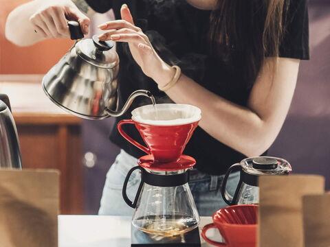 Frau gießt heißes Wasser in Handfilter