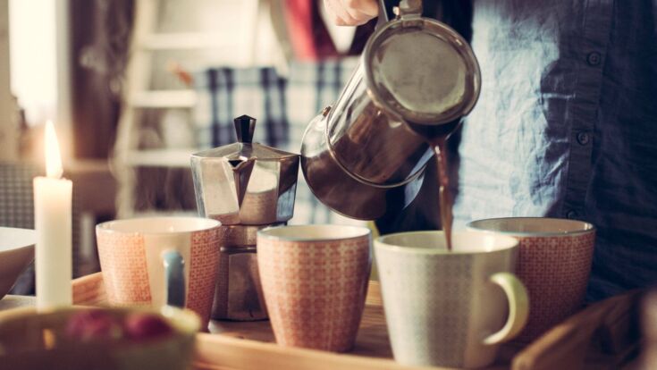 Kaffee wird aus einem Espressokocher in Tassen gegossen