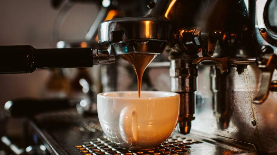 Espresso läuft aus einem Siebträger in eine weiße Porzellantasse