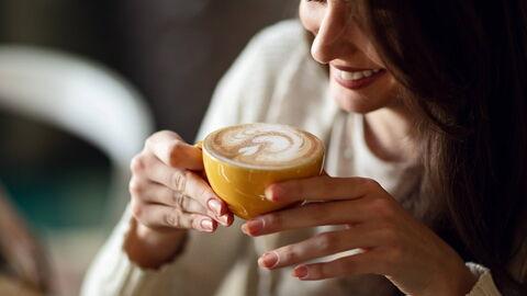 junge Frau trinkt Kaffee aus einer gelben Tasse