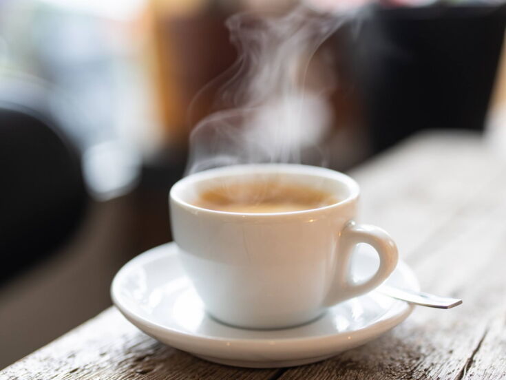 Ein frisch gebrühter Kaffee auf einer Untertasse steht auf einem Holztisch