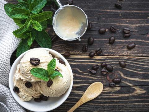 Eisbecher mit Kaffeebohnen auf einem Holztisch mit Holzlöffel