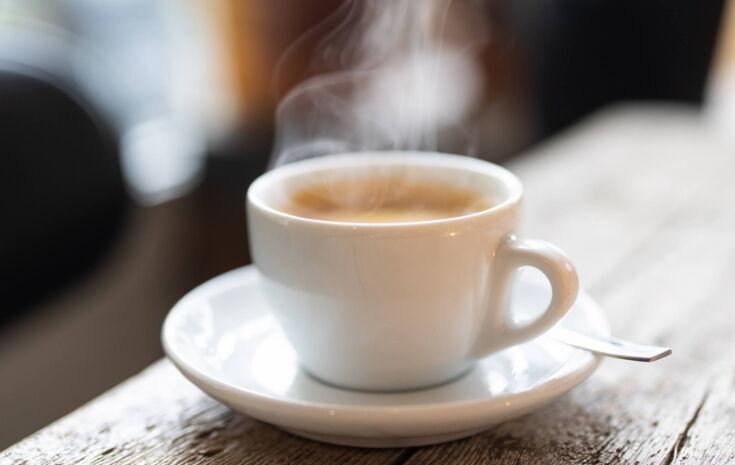 Ein frisch gebrühter Kaffee auf einer Untertasse steht auf einem Holztisch