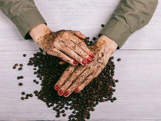 Damenhände reiben sich mit Kaffeepulver ein