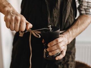 Barista benutzt eine handbetriebene Kaffeemühle