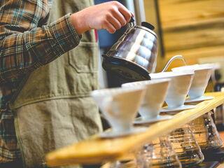 Ein Barista gießt heißes Wasser über eine Reihe Porzellan-Filter