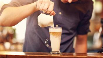 Mann gießt Espresso in Latte macchiato