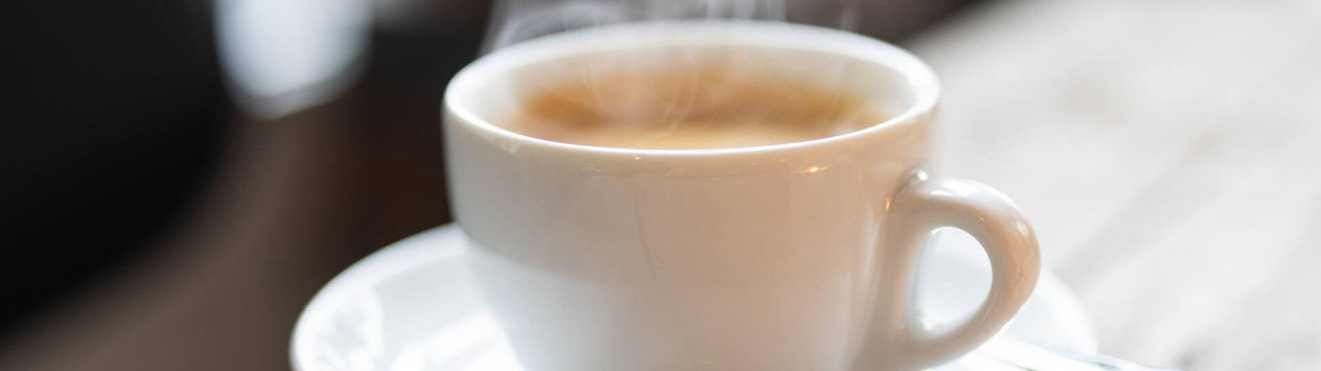 Ein frisch gebrühter Kaffee auf einer Untertasse steht auf einem Holztisch