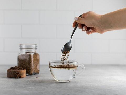 Frau rührt Instantkaffee in gekochtes Wasser