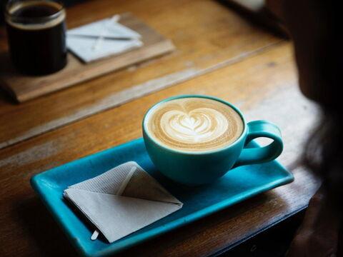 Tasse Kaffee wird mit Serviette auf Unterteller serviert