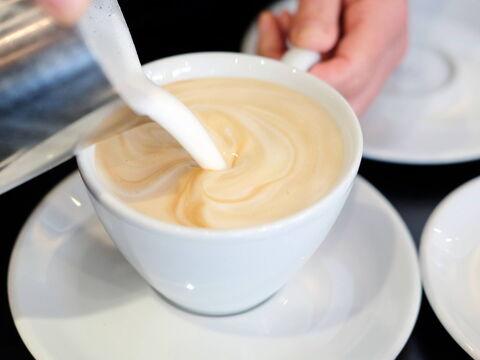 Milch wird in einem Kaffee gekippt