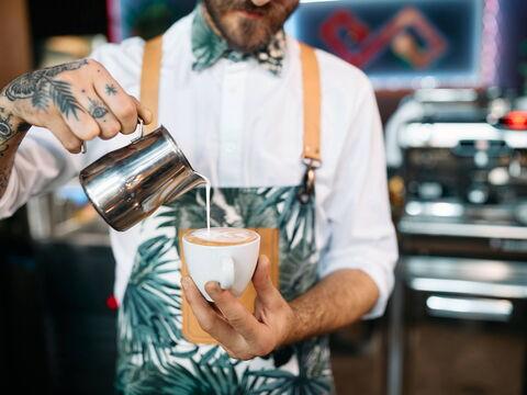 Barista arbeitet an der Bar und bereitet Latte-Art vor