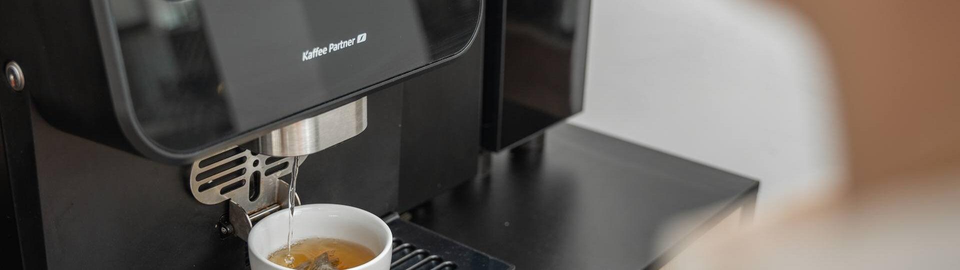 Heißwasser läuft in eine Tasse aus einem Kaffeevollautomaten