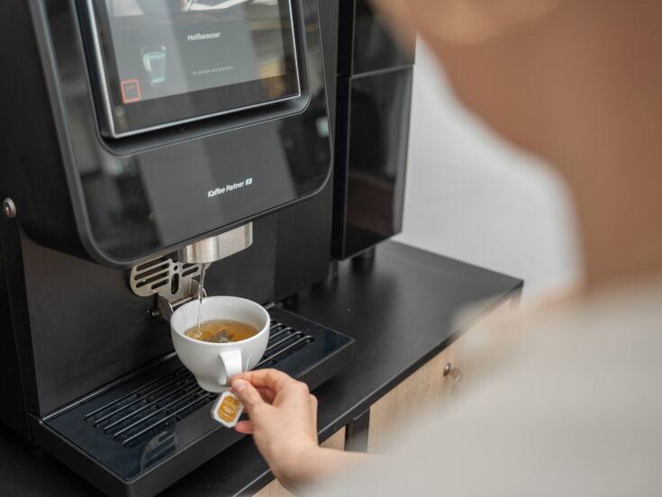 Heißwasser läuft in eine Tasse aus einem Kaffeevollautomaten