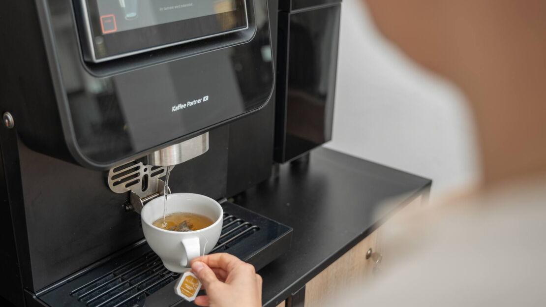 Heißwasser läuft in eine Tasse aus einem Kaffeevollautomaten