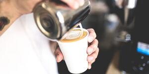 Mann macht Latte Art Herz in Becher