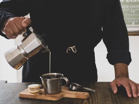 Mann schenkt Kaffee aus dem Espressokocher in eine Tasse