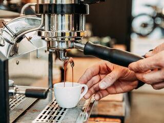 Barista arbeitet an der Siebträgermaschine und bereitet ein Espresso vor