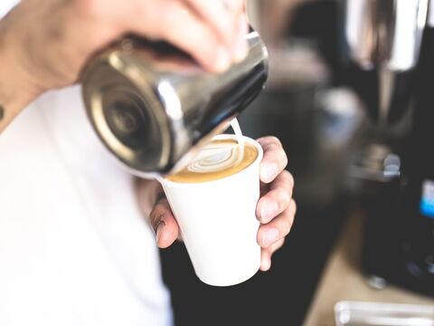 Mann macht Latte Art Herz in Becher