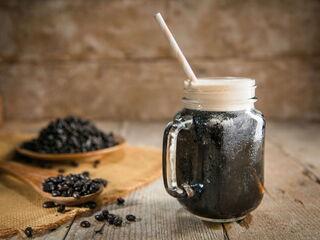 Kaffeeglas gefüllt mit Nitro Cold Brew Iced Coffee auf Holztisch