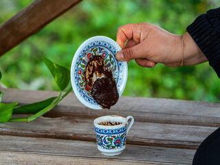 Person dreht eine traditionelle türkische Kaffeetasse um, um Kaffeesatz zu lesen.