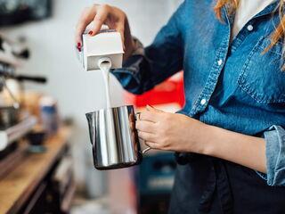 Barista gießt Milch in die Kanne