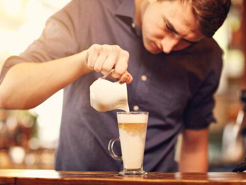 Mann gießt Espresso in Latte macchiato